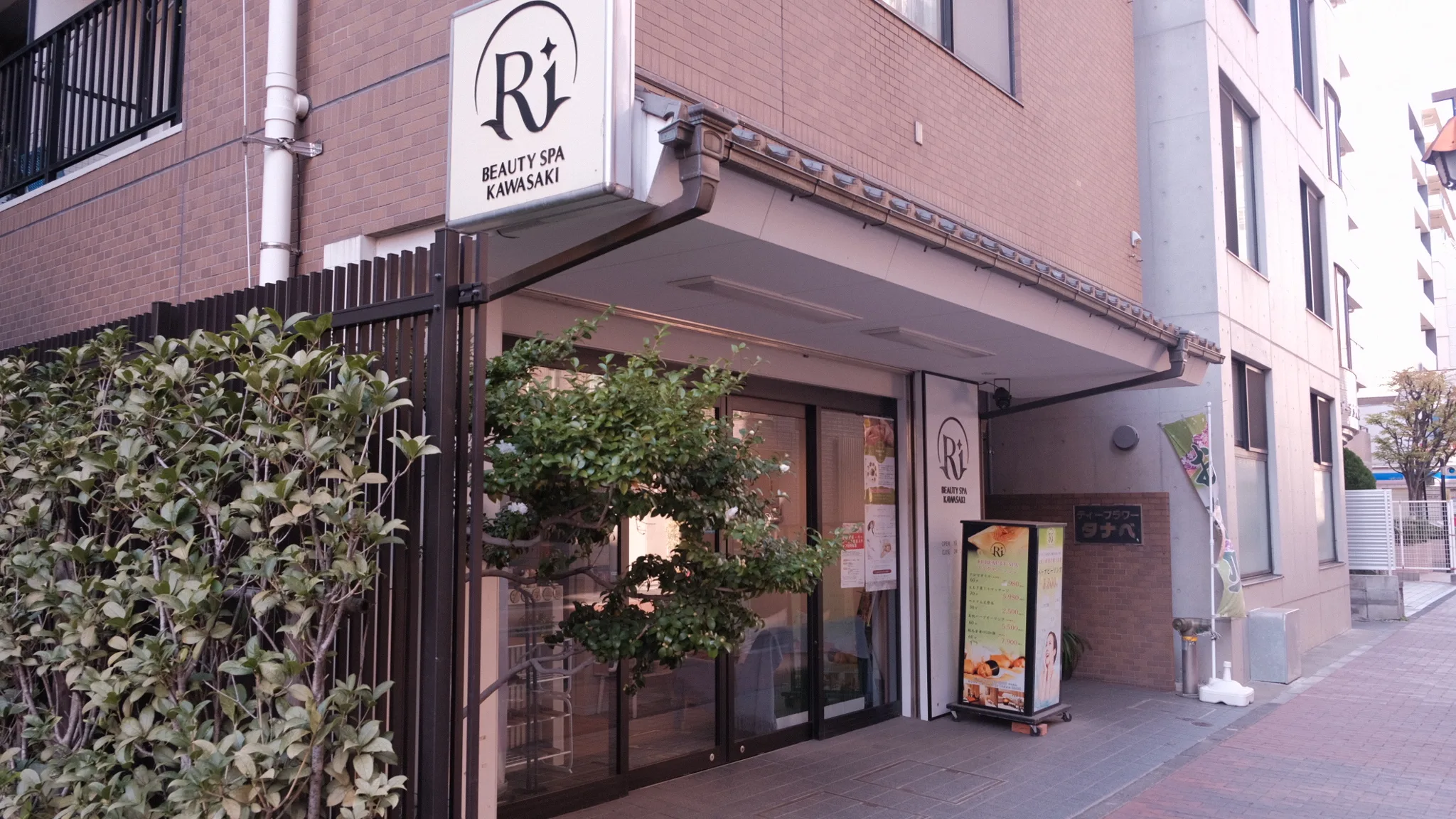 川崎市幸区の通り沿いにある建物の入口と、Ri Beauty Spa Kawasakiの看板が掲げられた店舗の外観